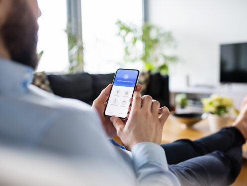 Man adjusting his smart thermostat and lighting in his Forest Lake home.